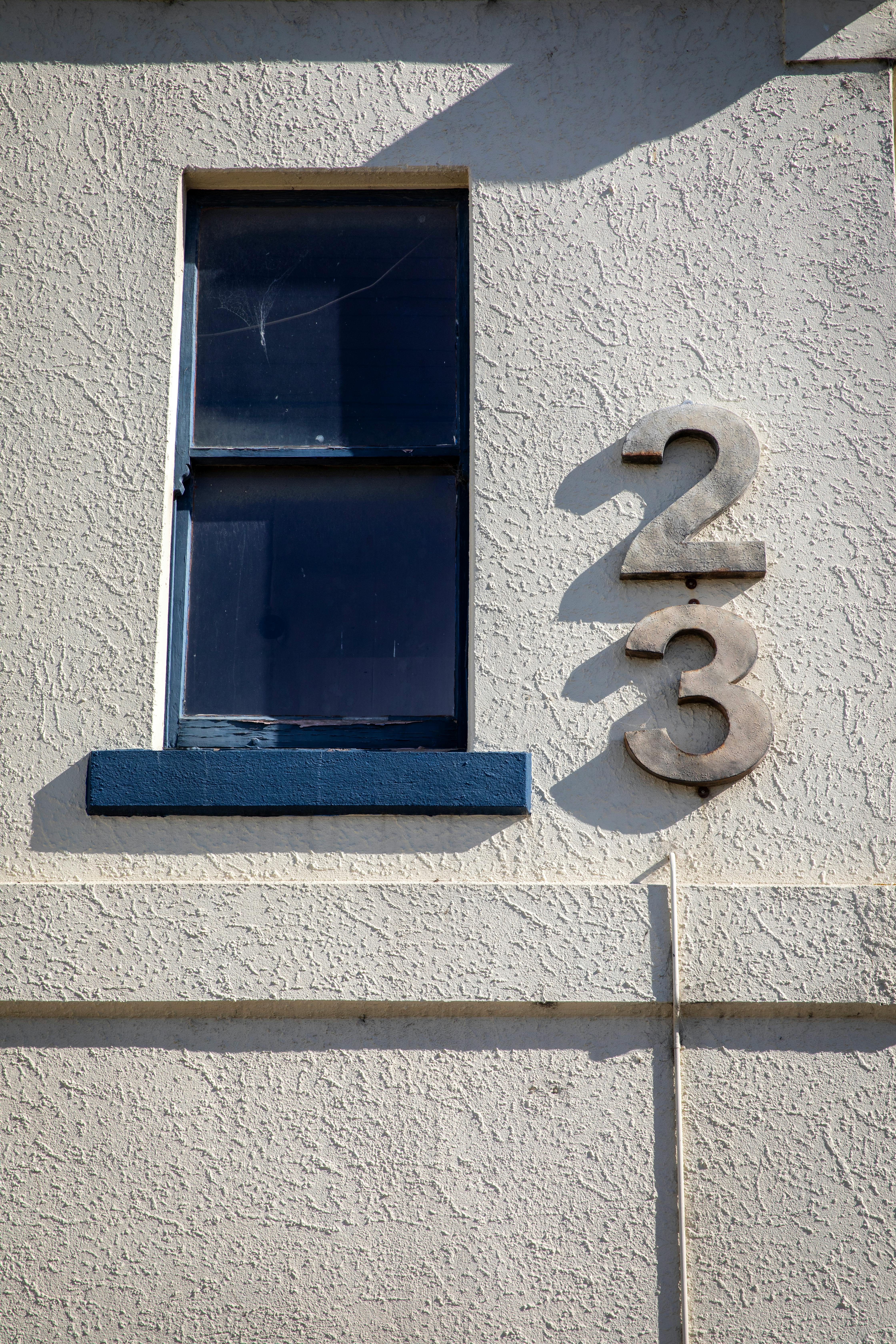 Close-up of a building facade featuring a window and the number 23.