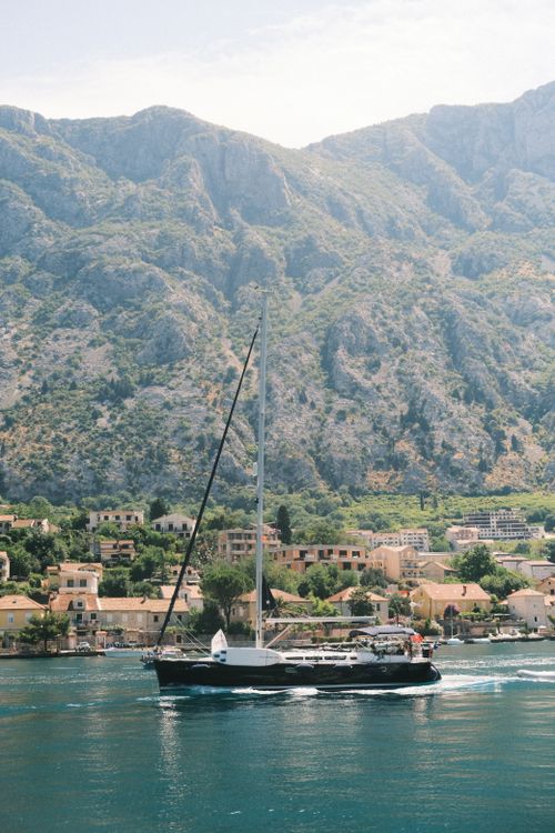 Free A serene view of a yacht sailing by the picturesque mountains in Kotor, Montenegro. Stock Photo