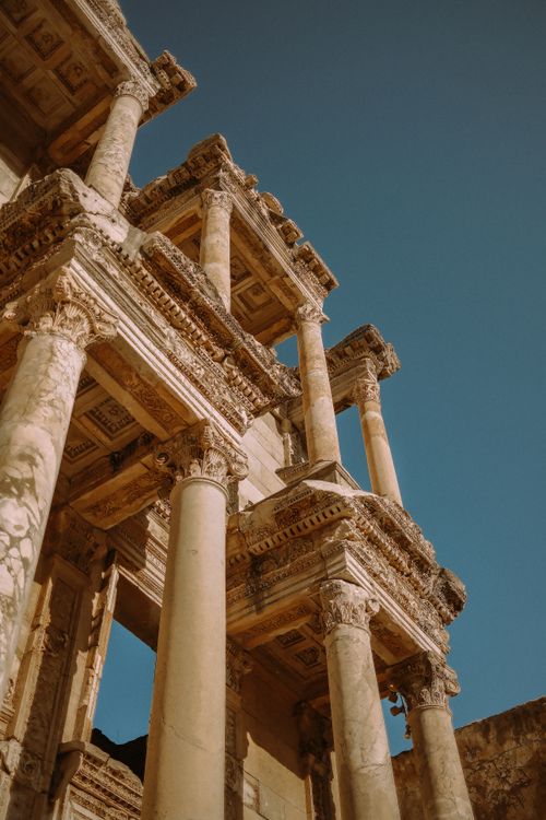 Free Ancient Roman architecture with intricate columns against a bright blue sky, showcasing historic grandeur. Stock Photo