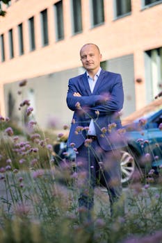 Confident businessman in suit standing outdoors amidst urban flowers.