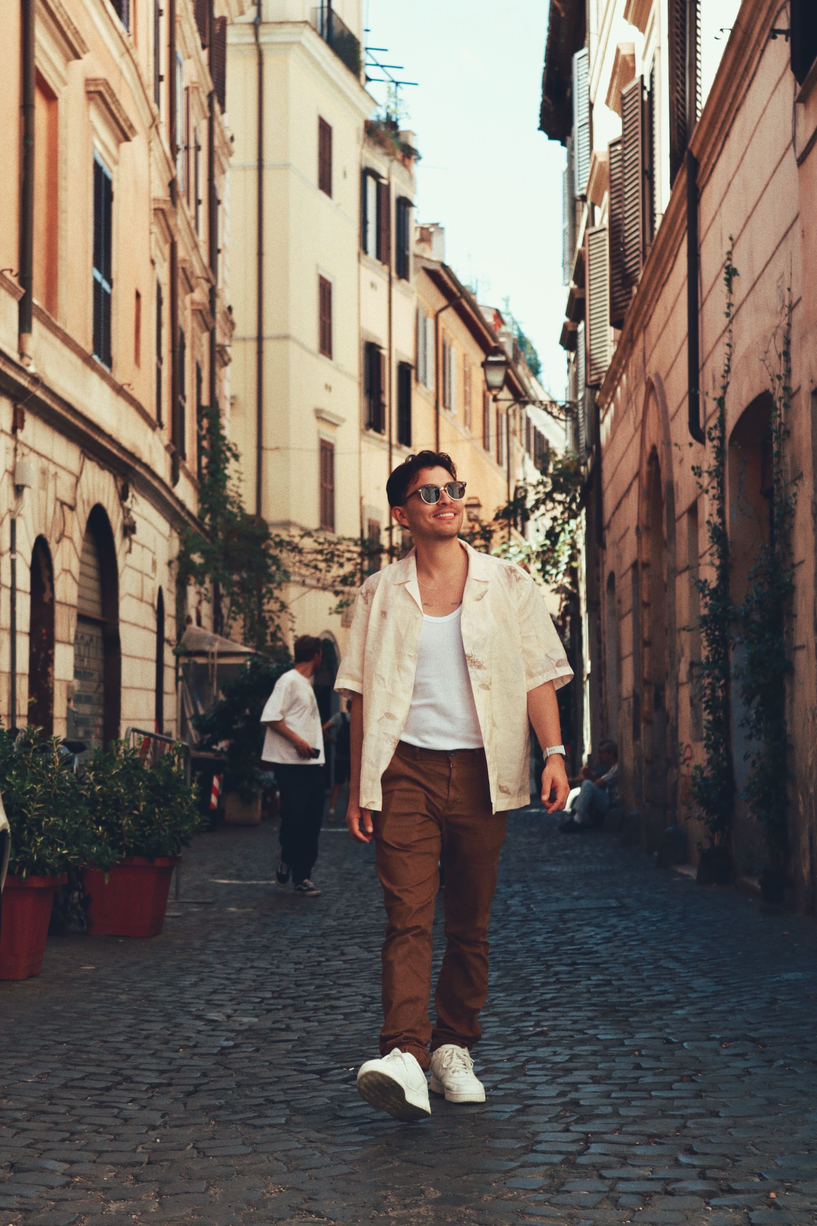 Fashionable young man walking on a charming cobblestone street in Rome, Italy.