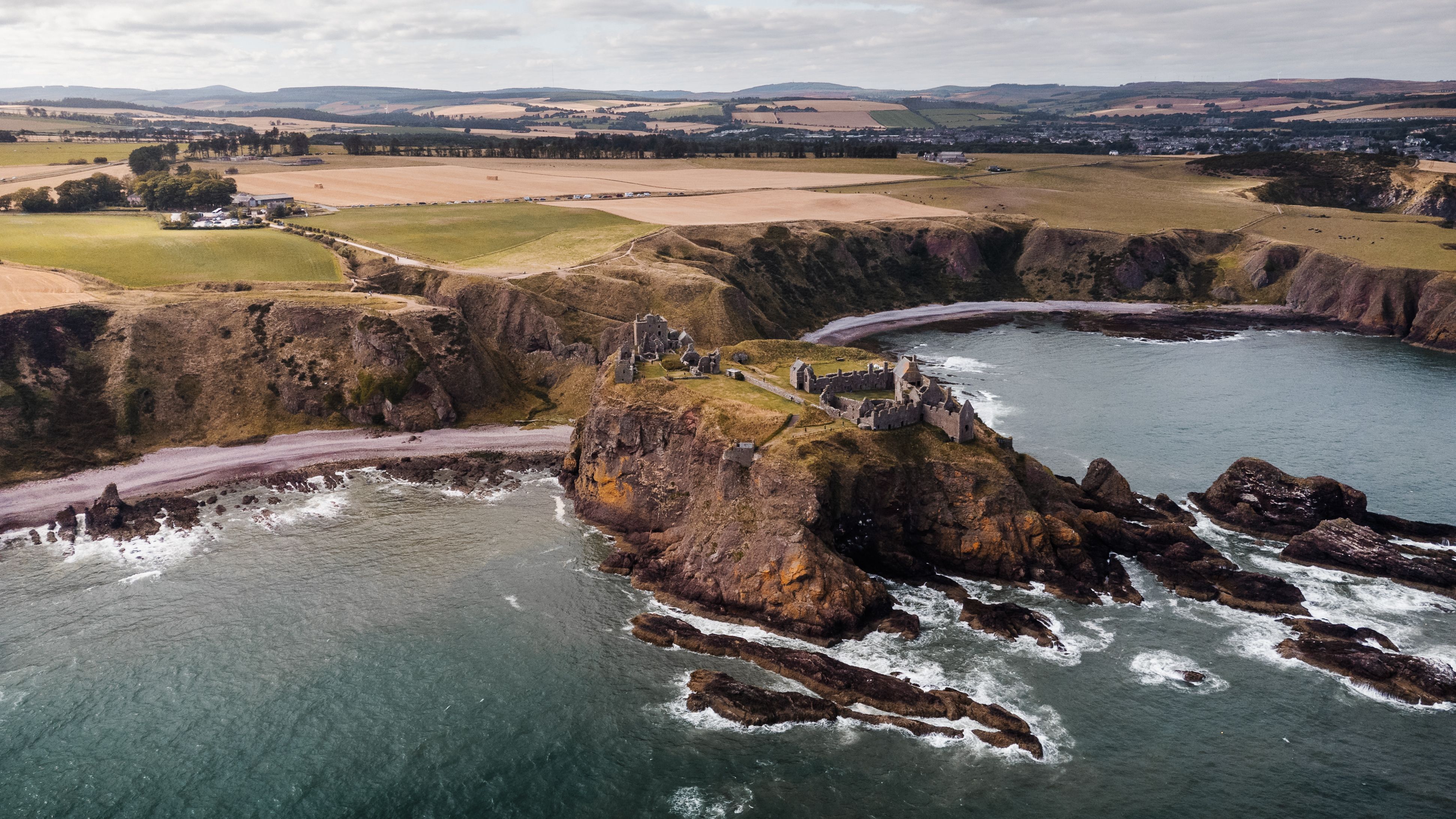 Aerial view of iconic Dunnottar Castle on a dramatic Scottish coastline.