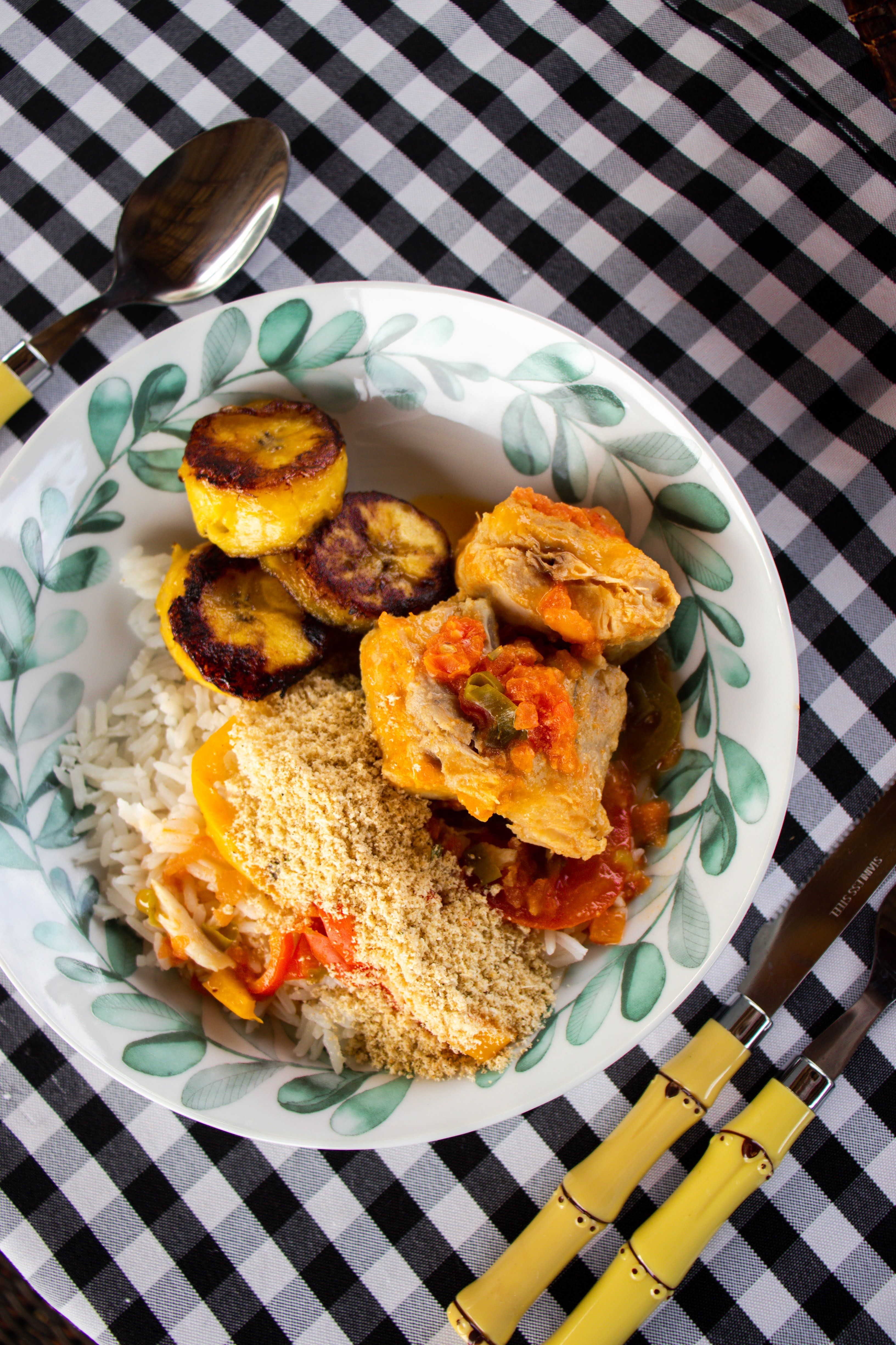 Letícia Alvares - Savor a vibrant Brazilian meal featuring rice, chicken, fried plantains, and farofa on a checkered table.