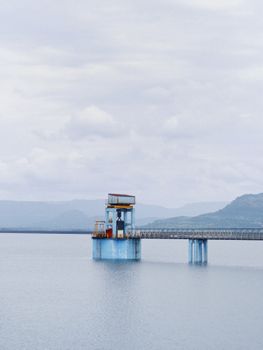 A serene water structure surrounded by mountains on a cloudy day.
