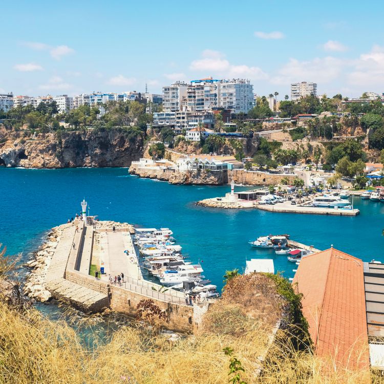 Free Beautiful aerial view of Antalya's picturesque harbor with boats and cliffs under a bright blue sky. Stock Photo