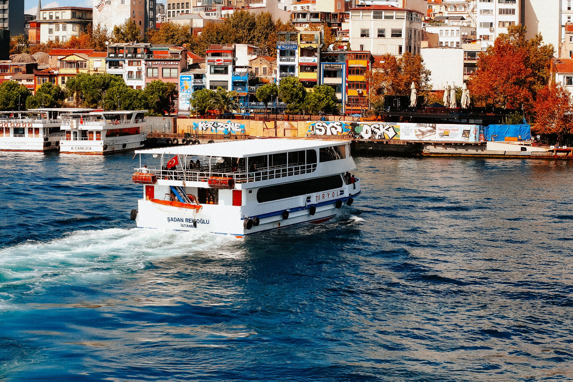 A vibrant cruise ship sailing in Istanbul with colorful cityscape backdrop.