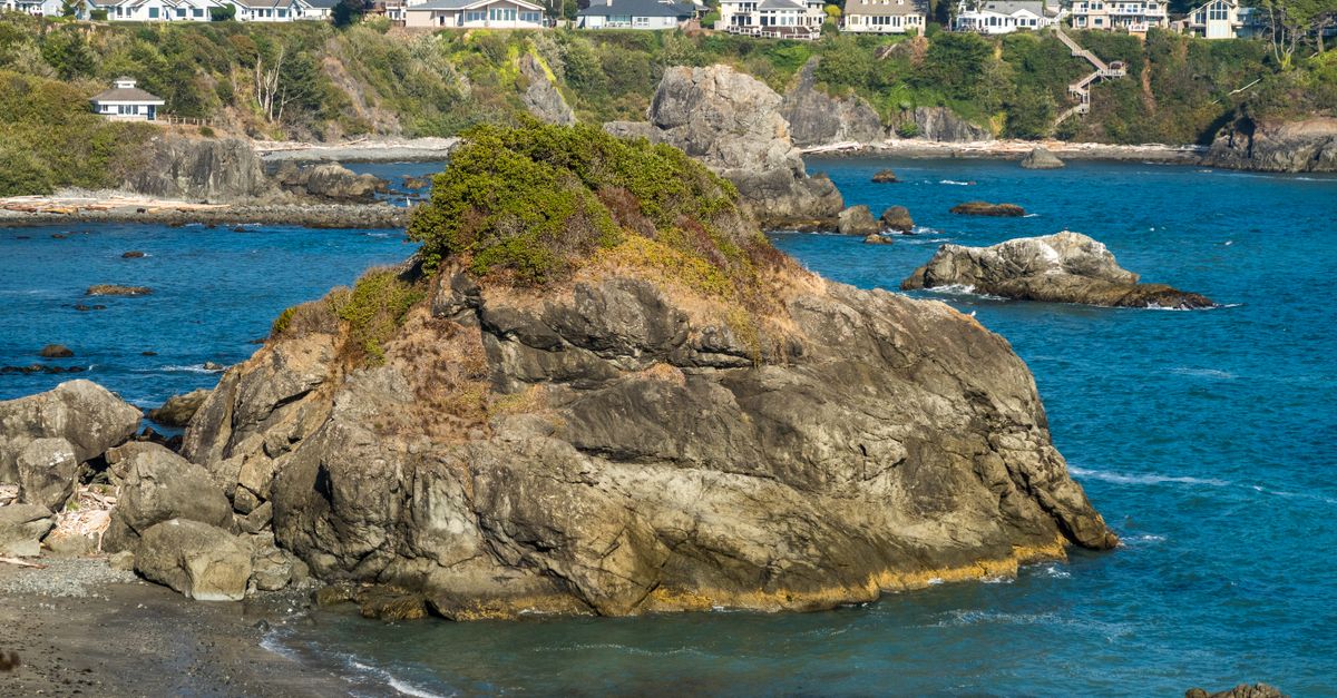 Stunning coastal scene with rocky cliffs and distant houses by the sea.