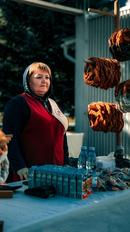 Free Woman selling traditional sausages at outdoor market stall. Stock Photo