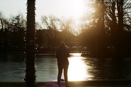 日の出の間に湖の近くに立っている女性