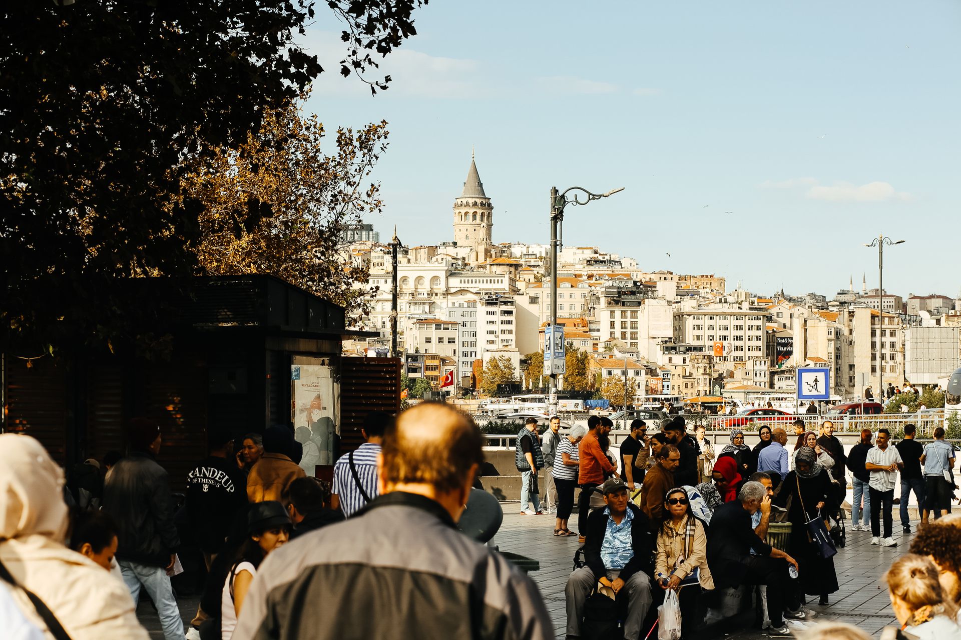 A busy day near Galata Tower in Istanbul with diverse crowds under clear skies.