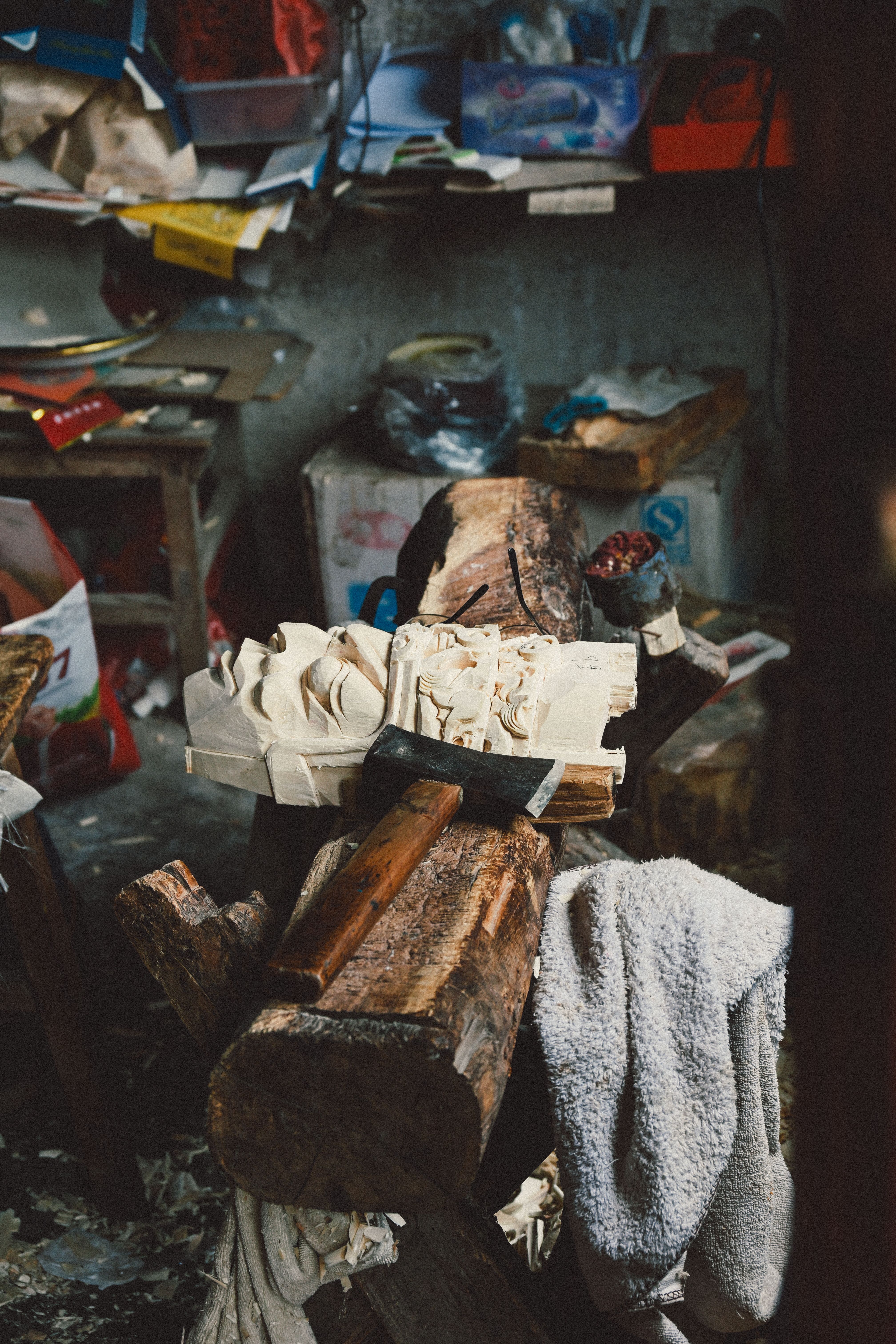 Detailed image of a wood carving process in a rustic workshop setting, showcasing tools and artisanal craftsmanship.