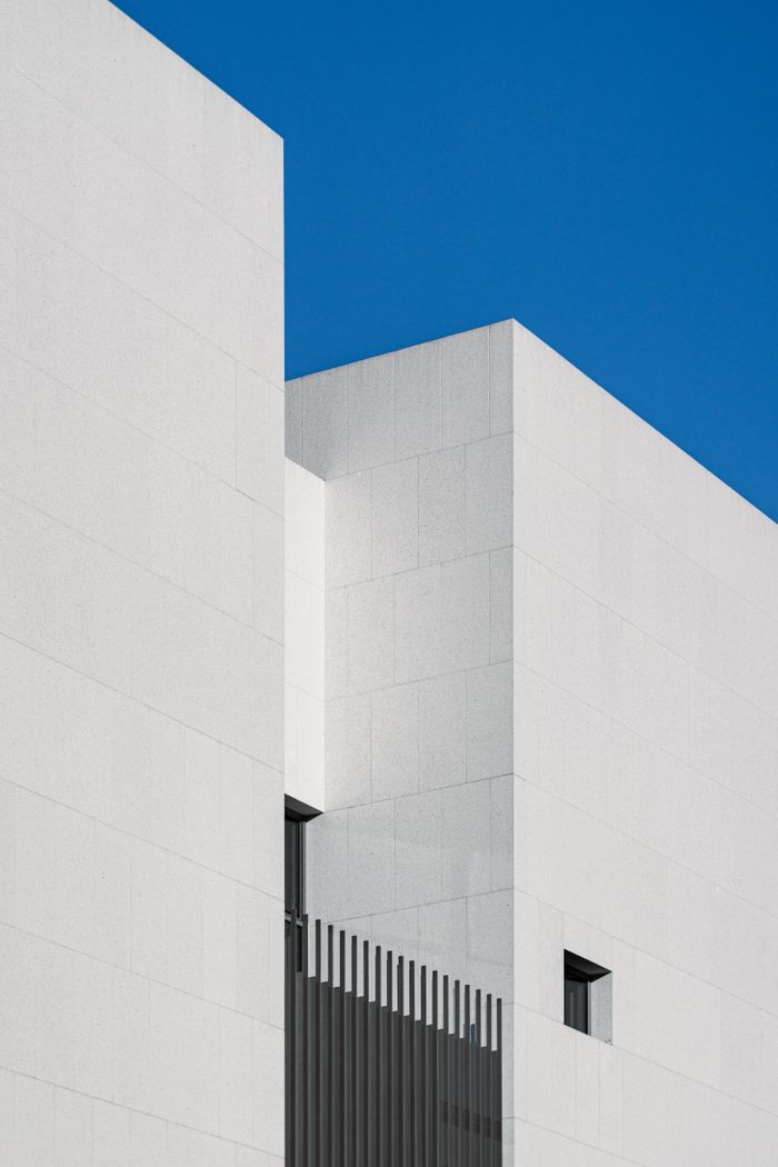 White minimalist building facade with geometric lines under a clear sky — photo by Volker Thimm on Pexels