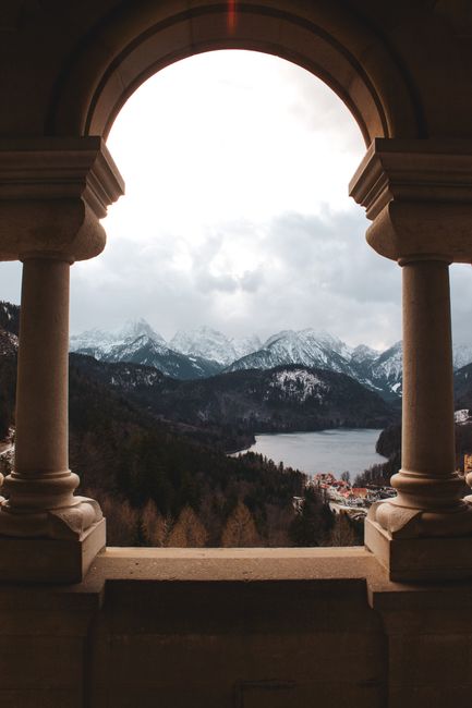 Breathtaking view of snow-capped Bavarian Alps framed by a stone arch in Schwangau, Germany.