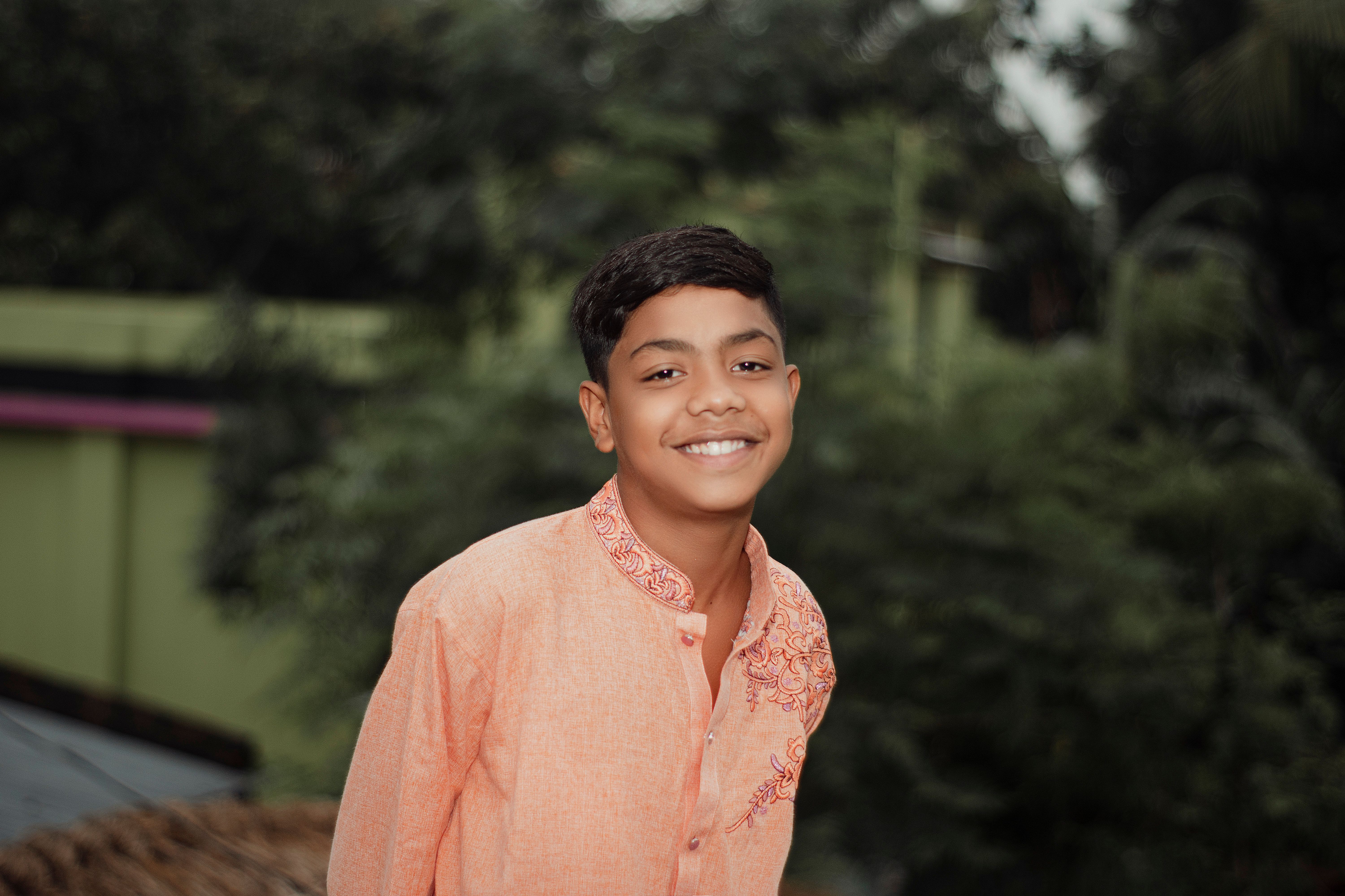 A vibrant outdoor portrait of a young boy in traditional attire, smiling warmly.