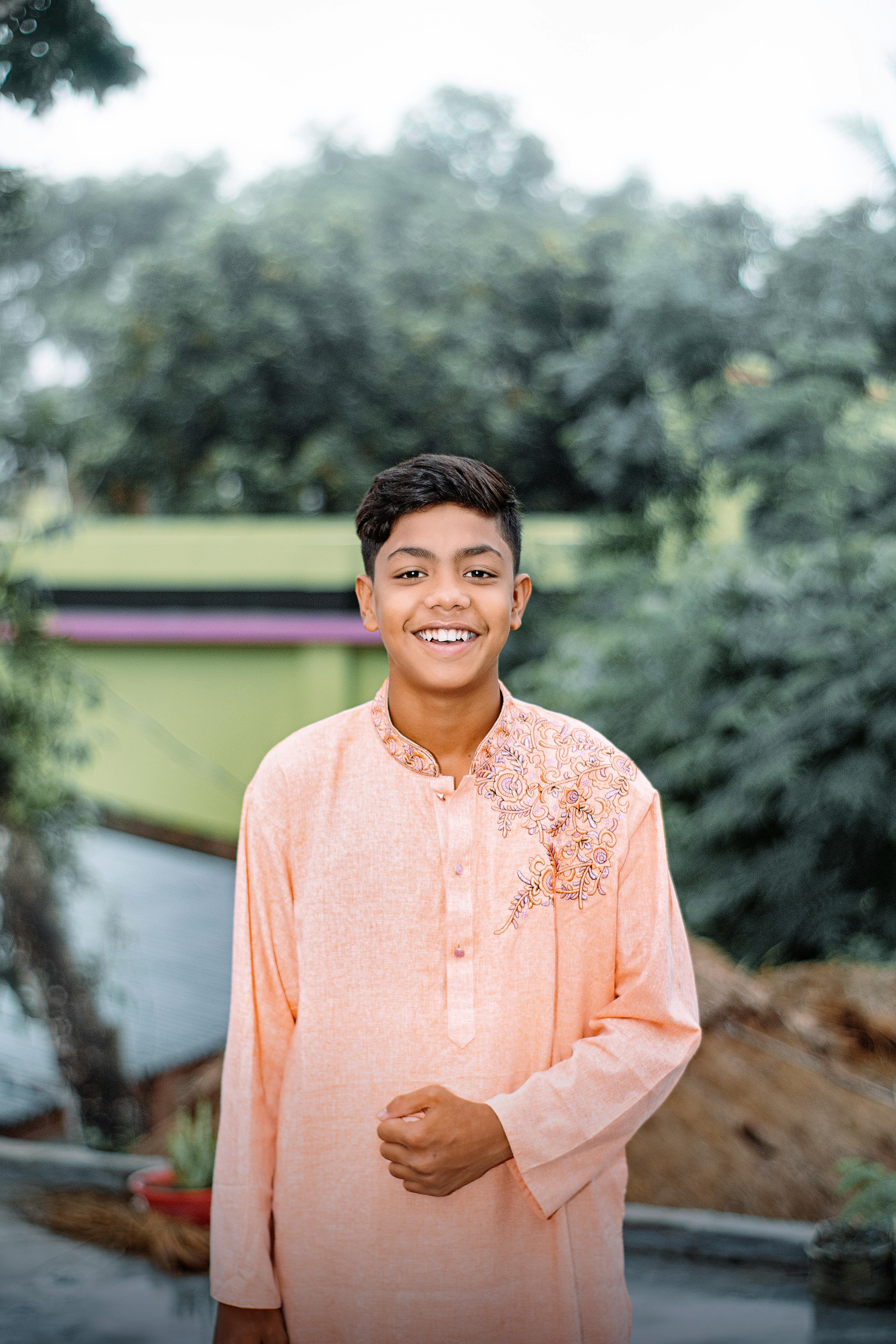 A cheerful teenager in traditional attire poses outdoors. Vibrant and lively setting.