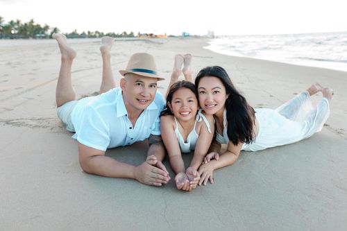 Free A joyful family of three enjoying a sunny day on the sandy beach of Hoi An, Vietnam. Stock Photo