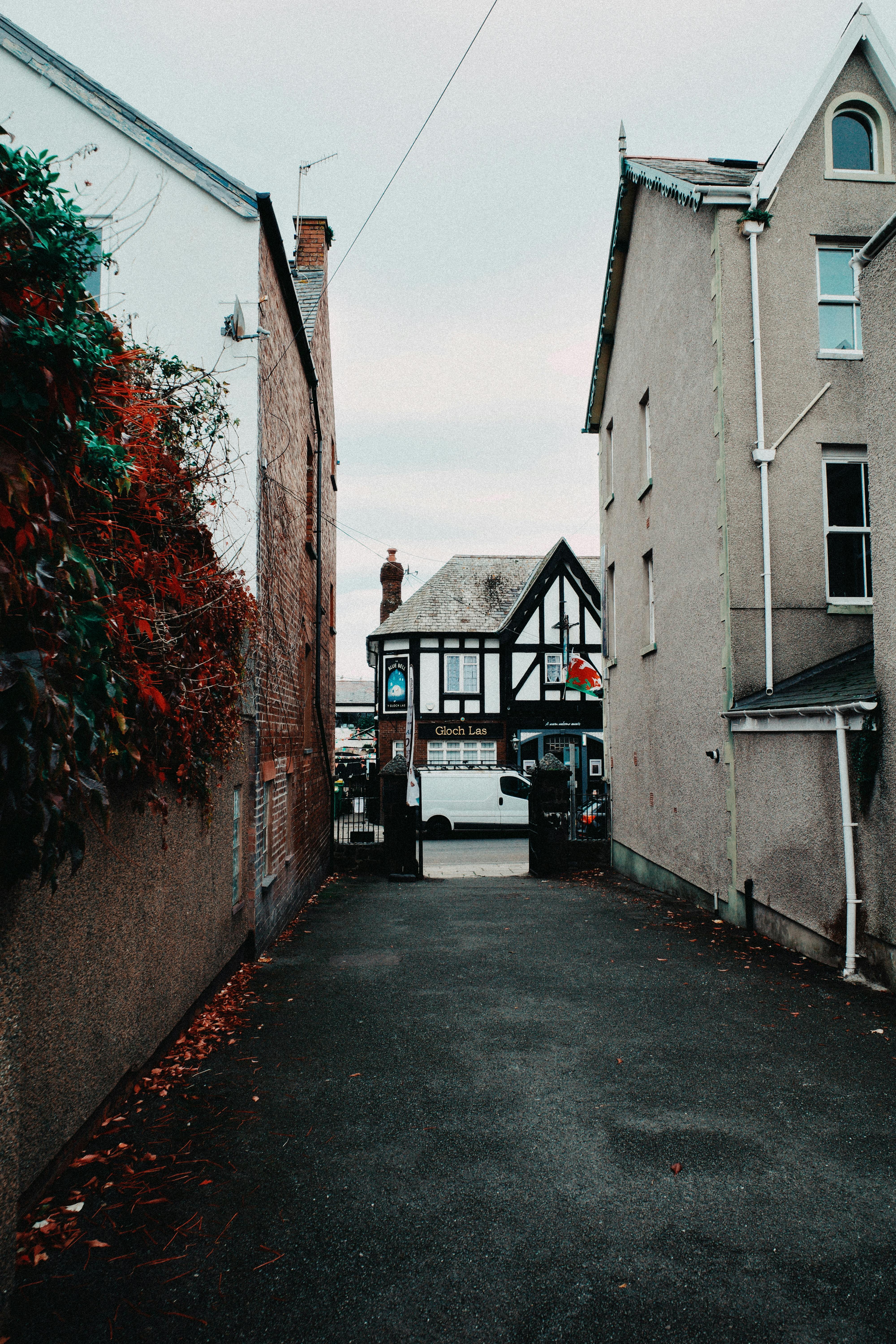 A picturesque alley in Conwy, Wales, leading to traditional architecture with fall foliage.