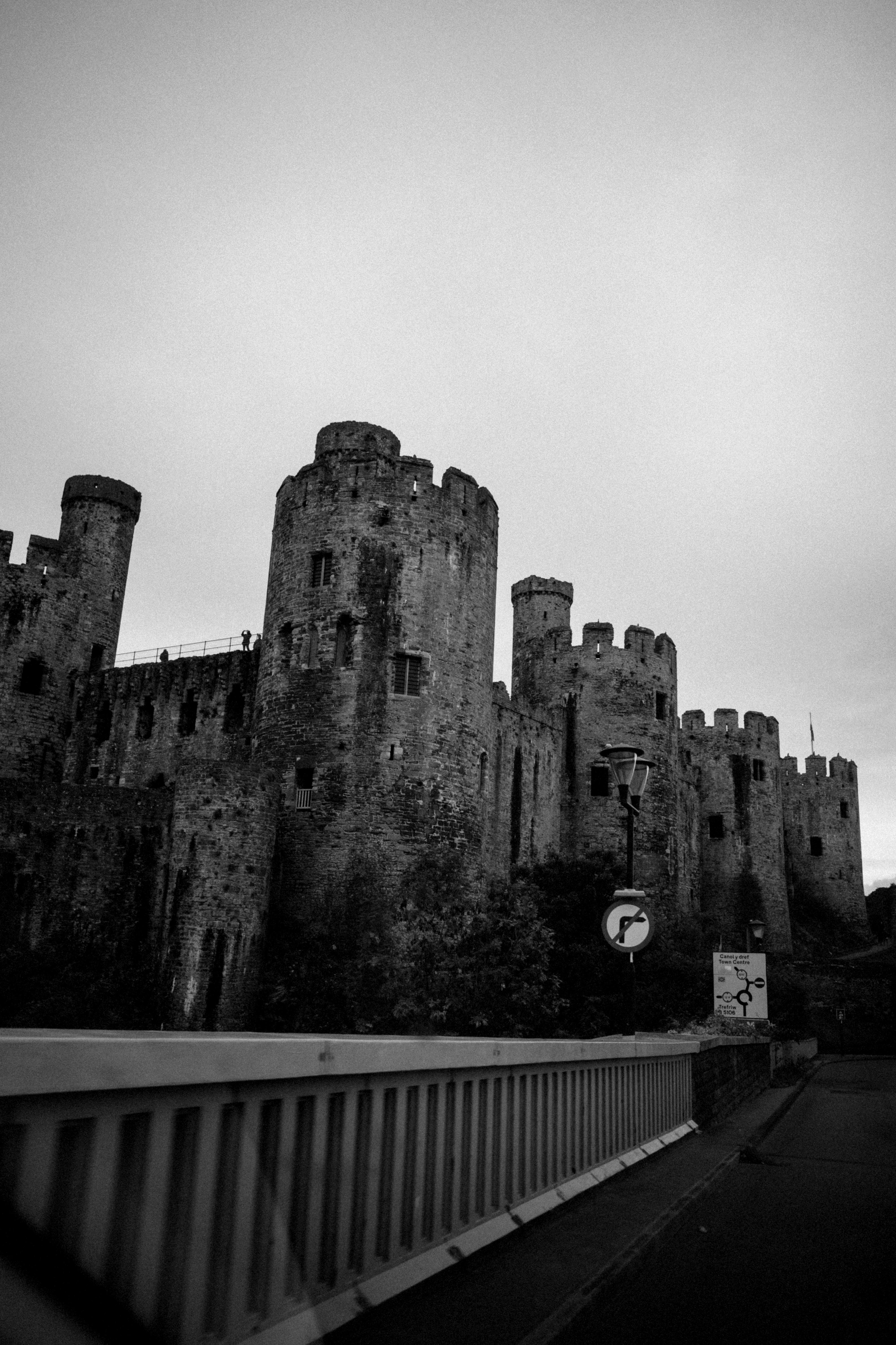 Black and white photo showcasing the historic Conwy Castle under a cloudy sky, Wales.