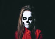 在黑色背景下，一位画着骷髅脸彩绘的女性肖像令人毛骨悚然，融合了艺术与时尚