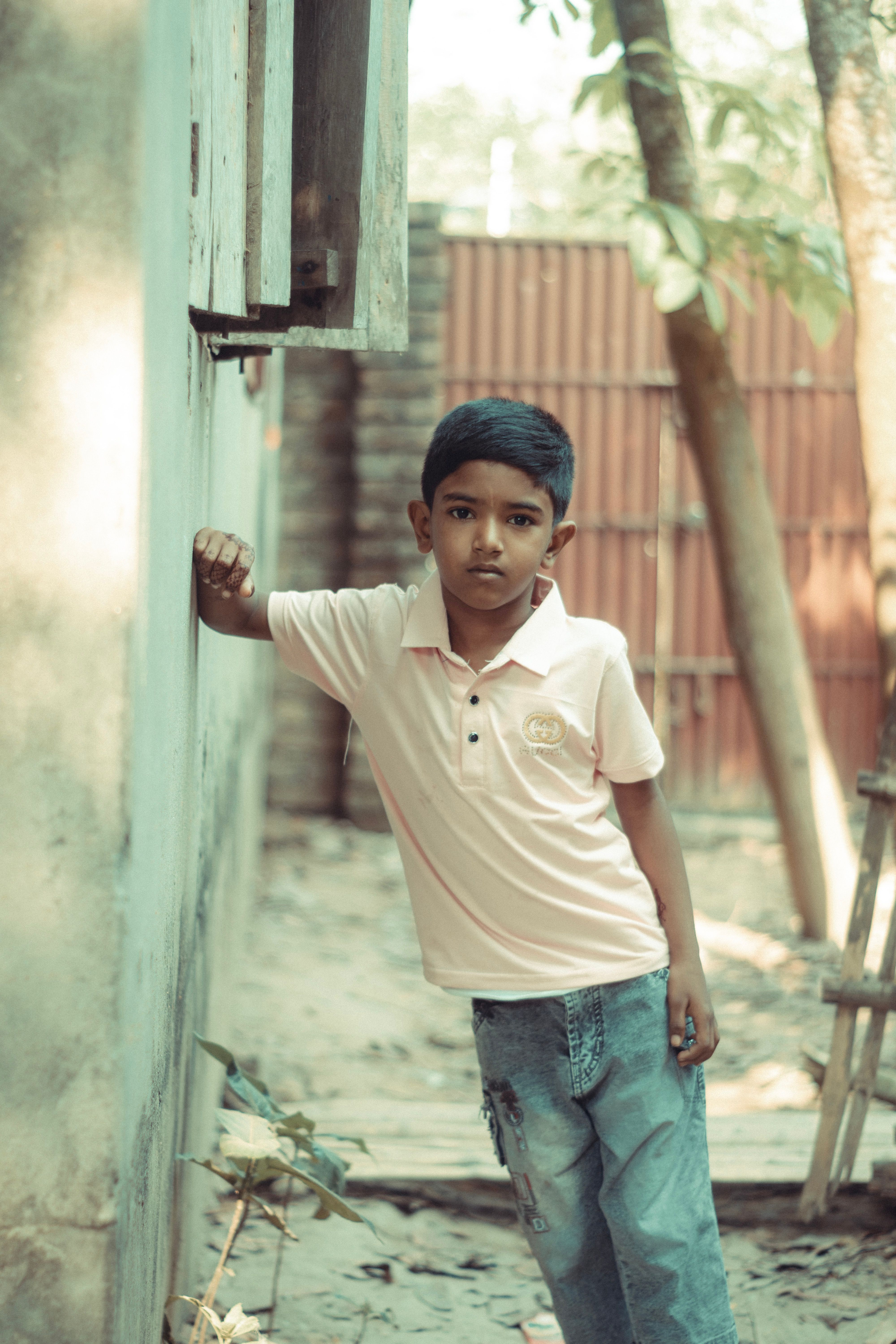 Young Boy Posing Outdoors in Village Setting · Free Stock Photo