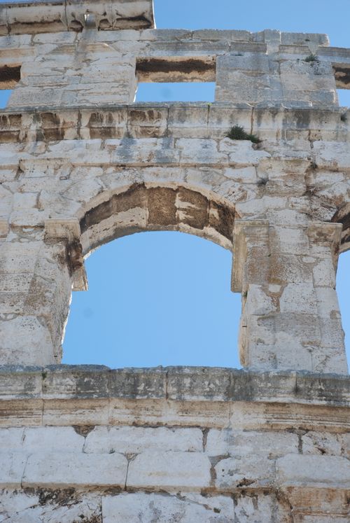 Free Close-up of the historic Pula Arena architecture under a clear blue sky. Stock Photo