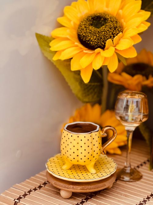 Free Charming yellow polka dot cup with vibrant sunflower, capturing a cheerful moment. Stock Photo