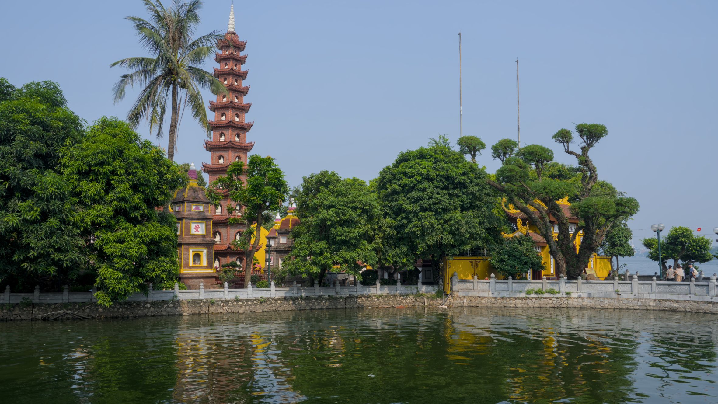 Scenic image of Tran Quoc Pagoda and lush trees reflecting in the serene lake in Hanoi, Vietnam.
