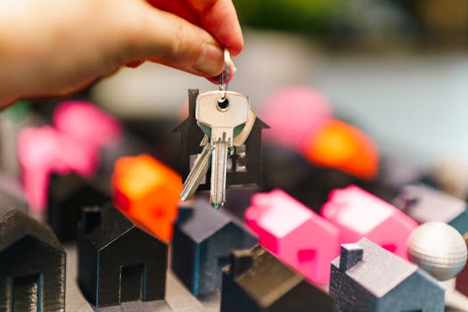 Photo by Jakub Zerdzicki Colorful miniature houses and a hand holding keys representing real estate decisions.