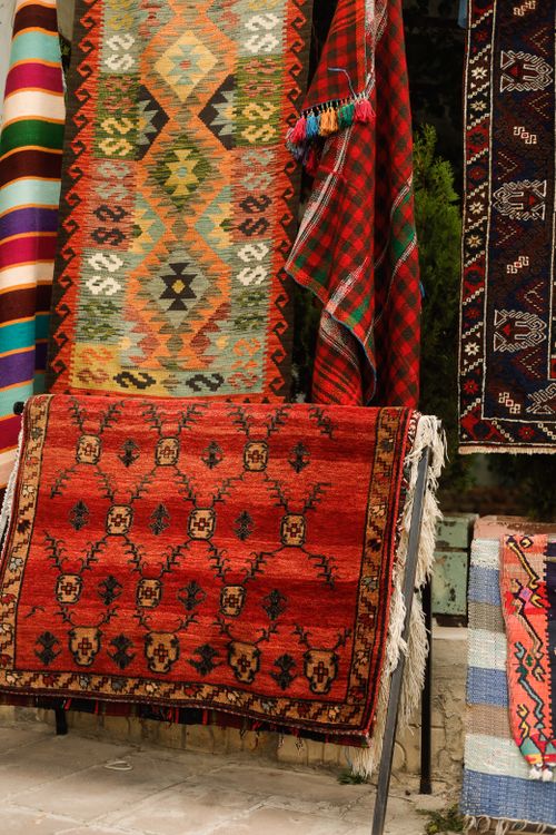 Free A colorful collection of traditional handwoven rugs displayed outdoors, showcasing intricate patterns and vivid colors. Stock Photo