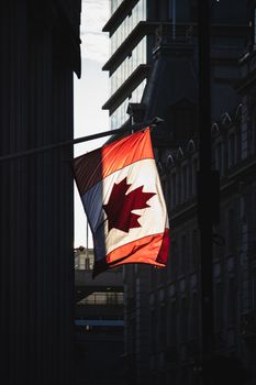 A Canadian flag waving prominently in a sunlit street in London, showcasing cultural diversity.