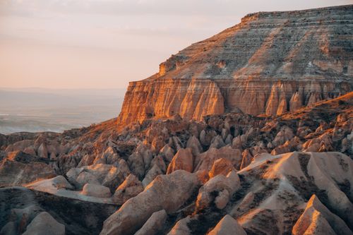 Free Stunning eroded landscape of Cappadocia at sunset with warm tones and dramatic shadows. Stock Photo
