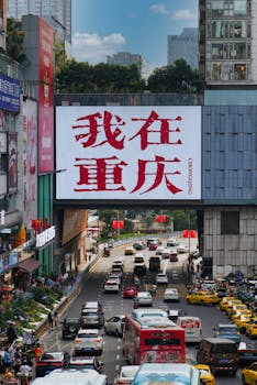 Busy urban scene in Chongqing with traffic under a prominent outdoor sign.