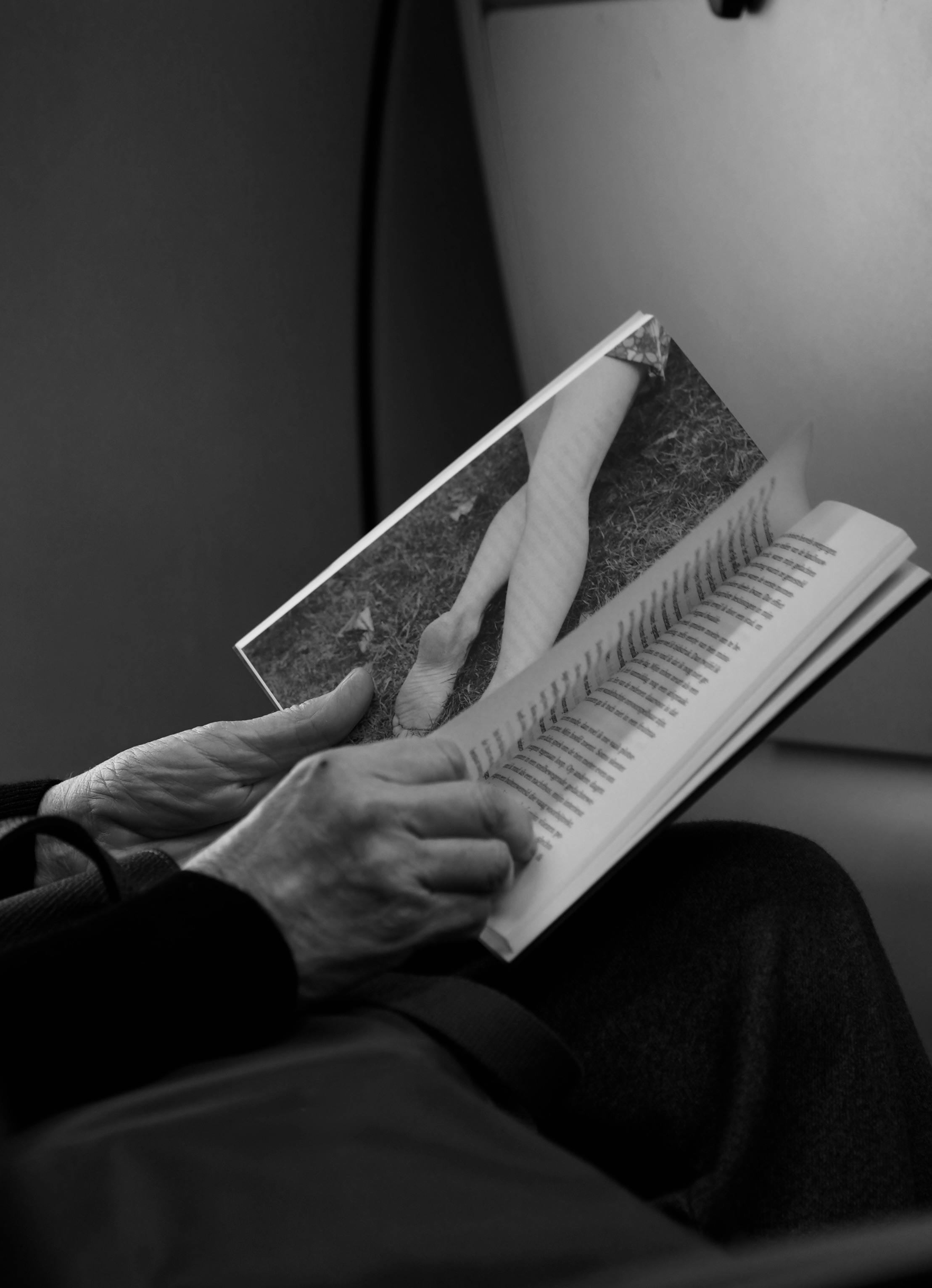 De franc Imatge en blanc i negre de mans que sostenen un llibre obert, revelant pàgines amb text i imatges. Foto d'estoc