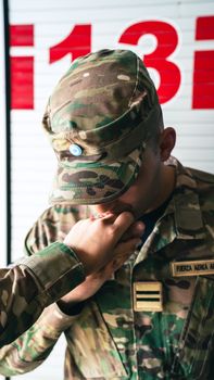 A military officer in camouflage receiving a respectful hand kiss indoors.