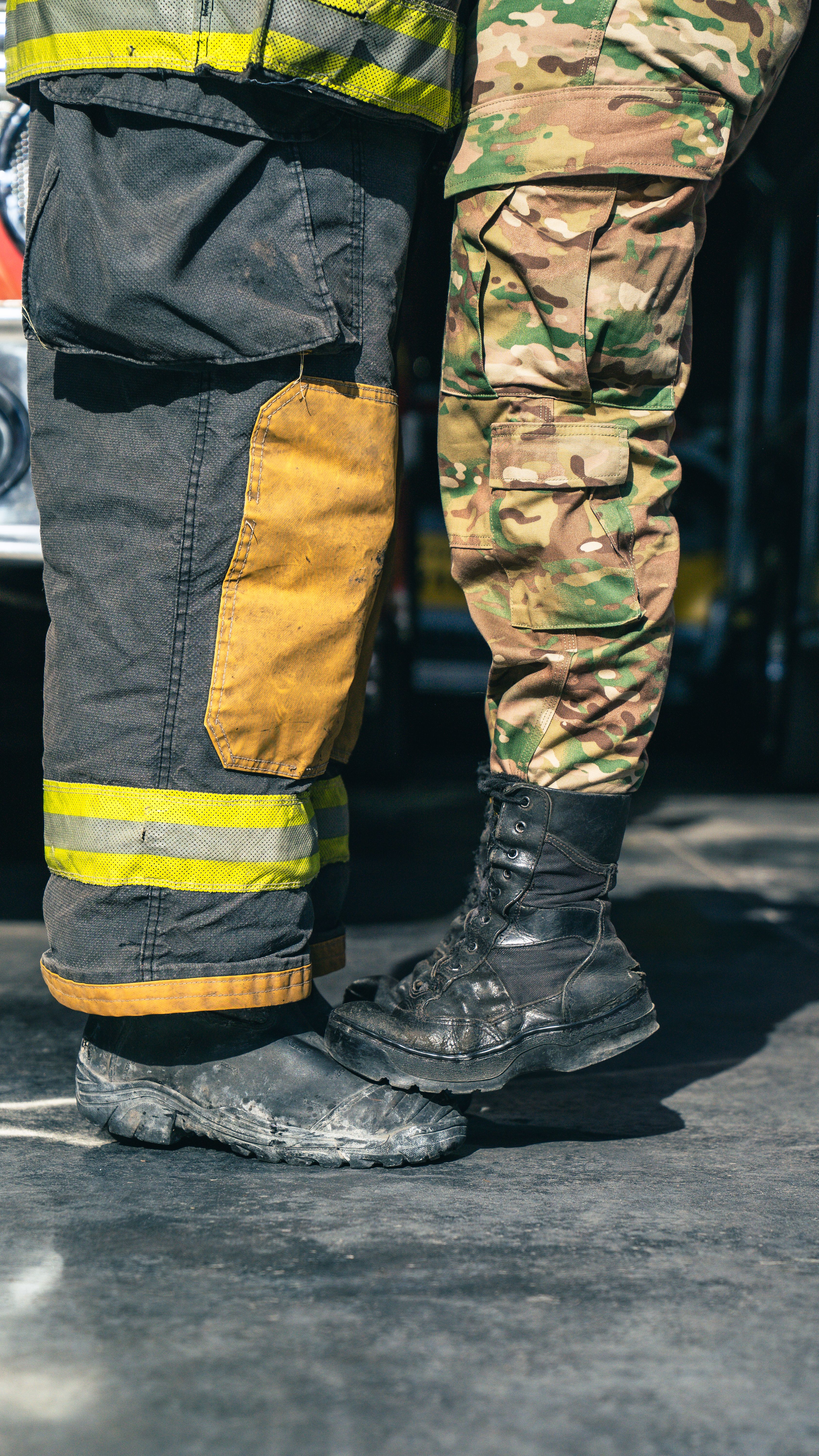 A close-up of a firefighter and a soldier in uniform hugging, illustrating unity.