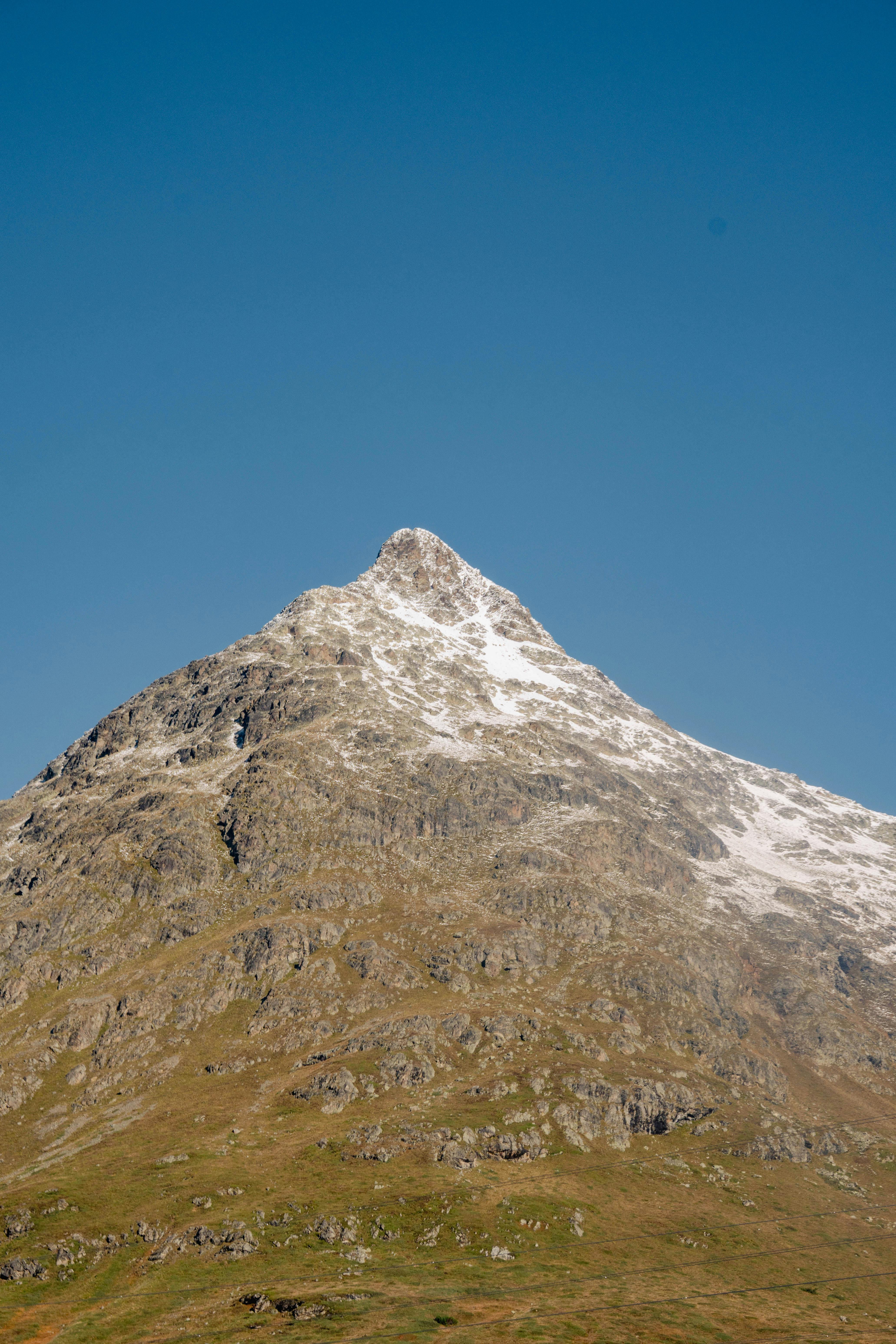 Majestic snow-covered mountain in Poschiavo, Switzerland under a clear blue sky.