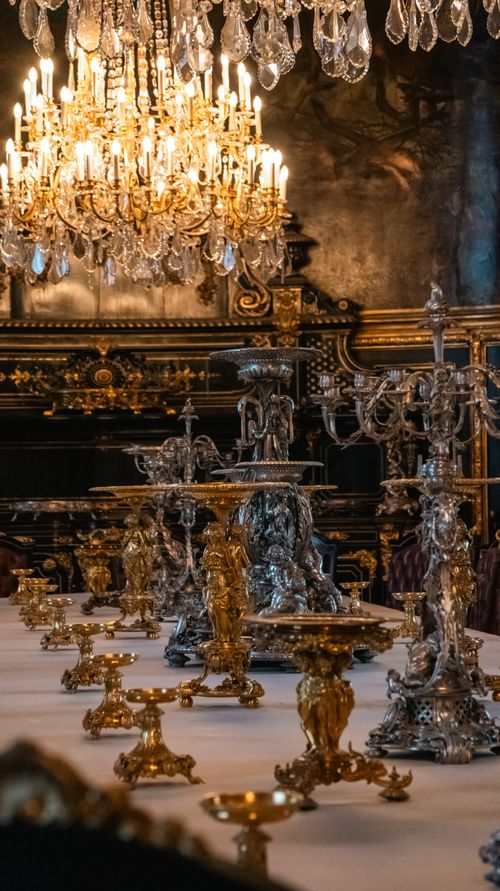 Free Opulent dining table with ornate candelabras beneath a grand chandelier in a lavish Parisian setting. Stock Photo