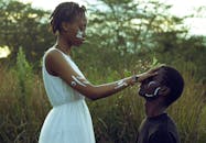 一对年轻的非洲夫妇脸上涂着颜料，在大自然中分享亲密时刻