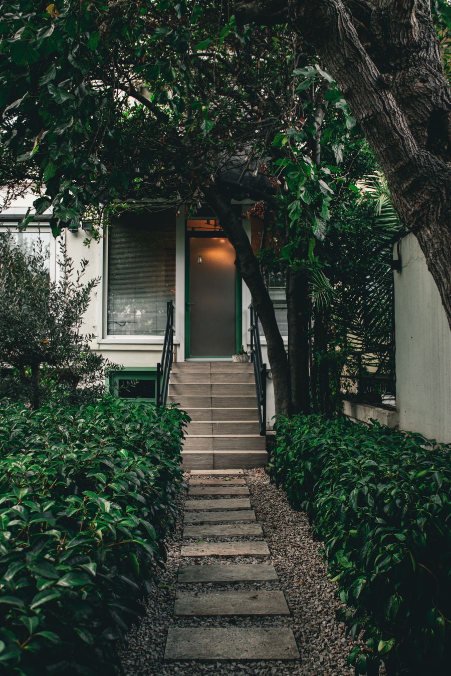 Home entrance framed by maintained shrubs and trees