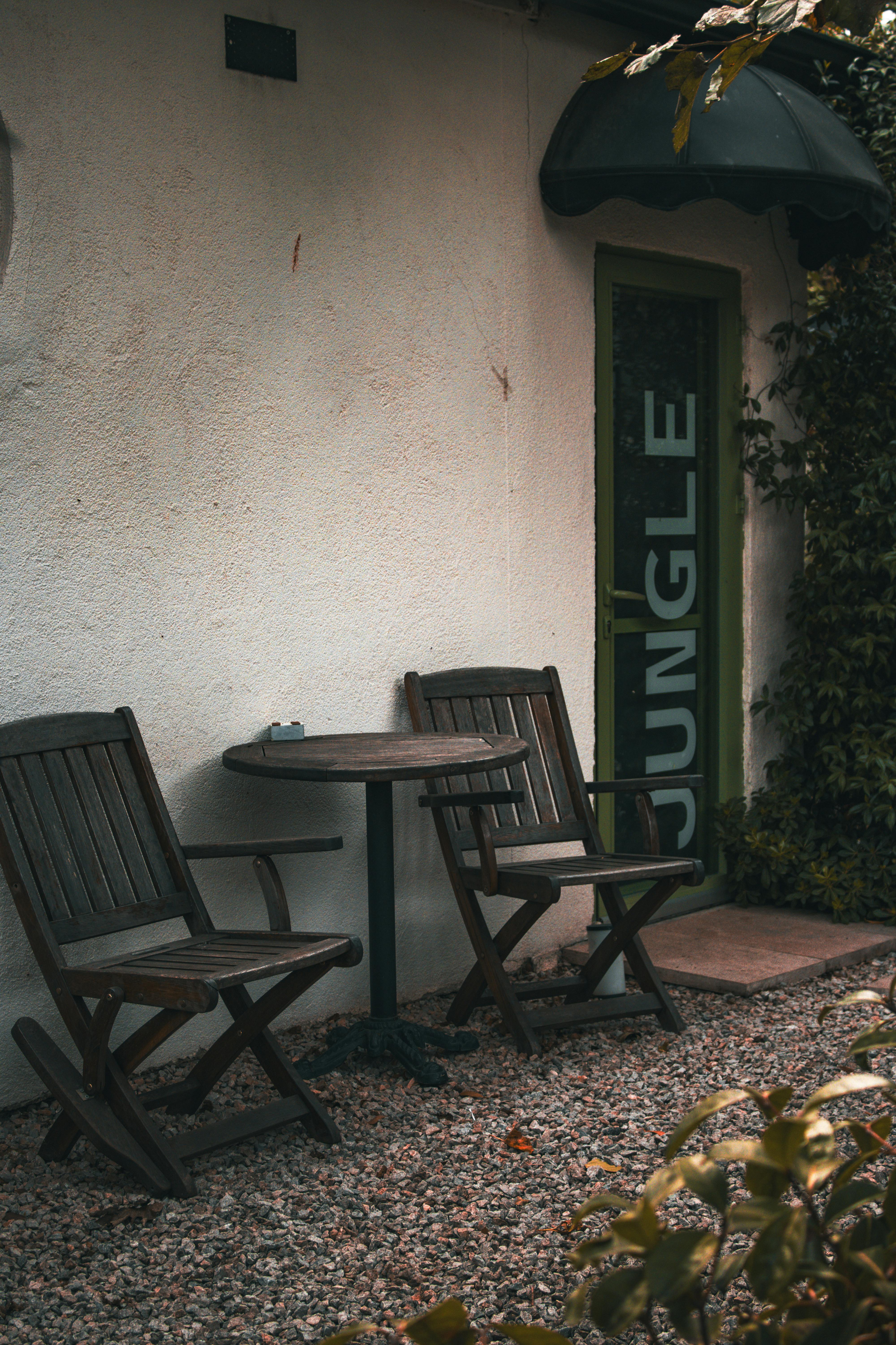 Gratuit Loc liniștit în aer liber, cu scaune și masă din lemn, lângă intrarea în cafeneaua Jungle. Fotografie de stoc