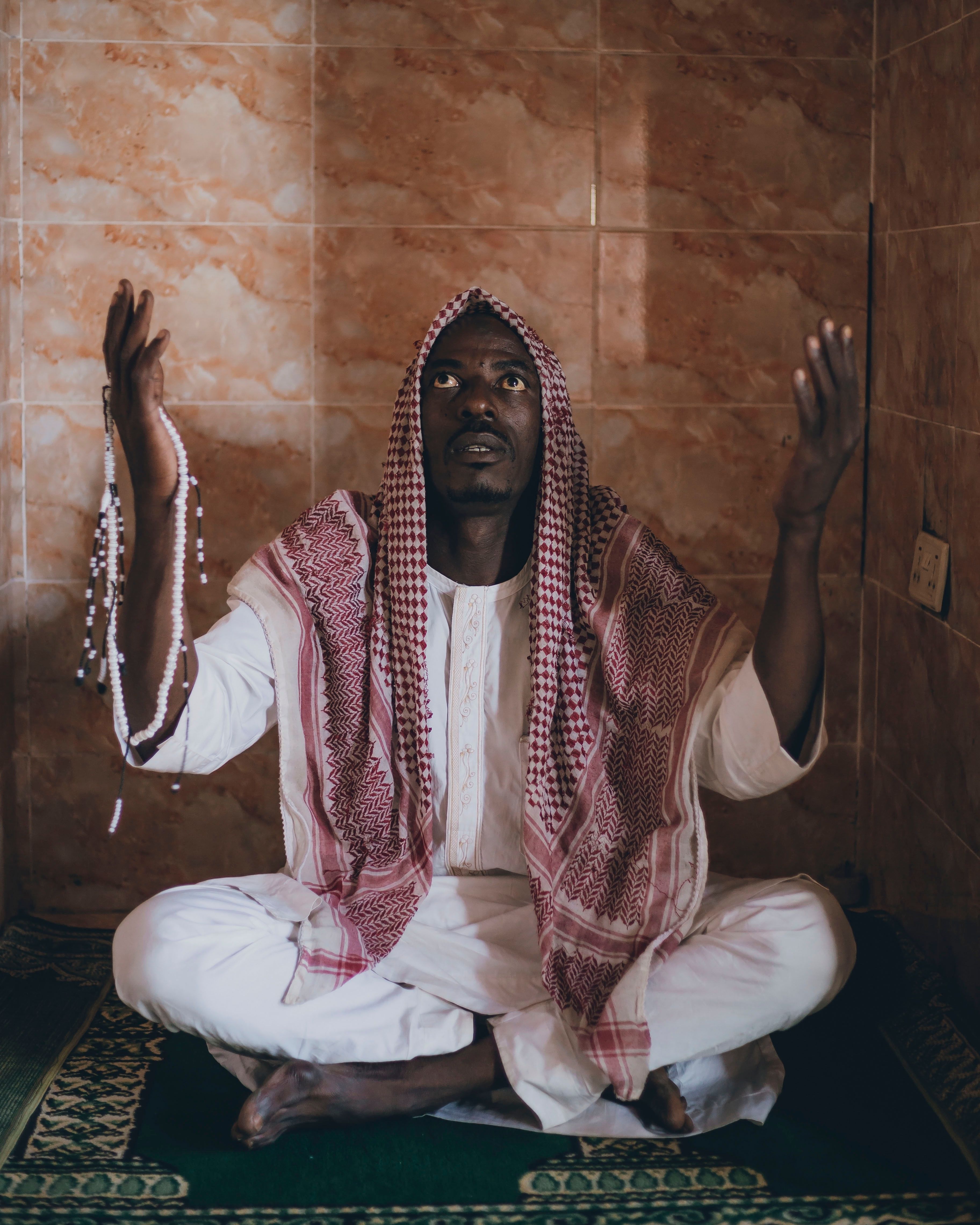 Man Praying Indoors with Prayer Beads · Free Stock Photo