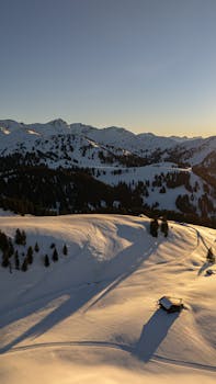 A stunning aerial shot of the snow-covered Alps during sunset in Graubünden, Switzerland.