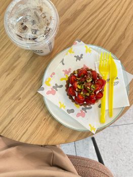 Top-down view of a strawberry tart with pistachios and iced coffee on a wooden table.