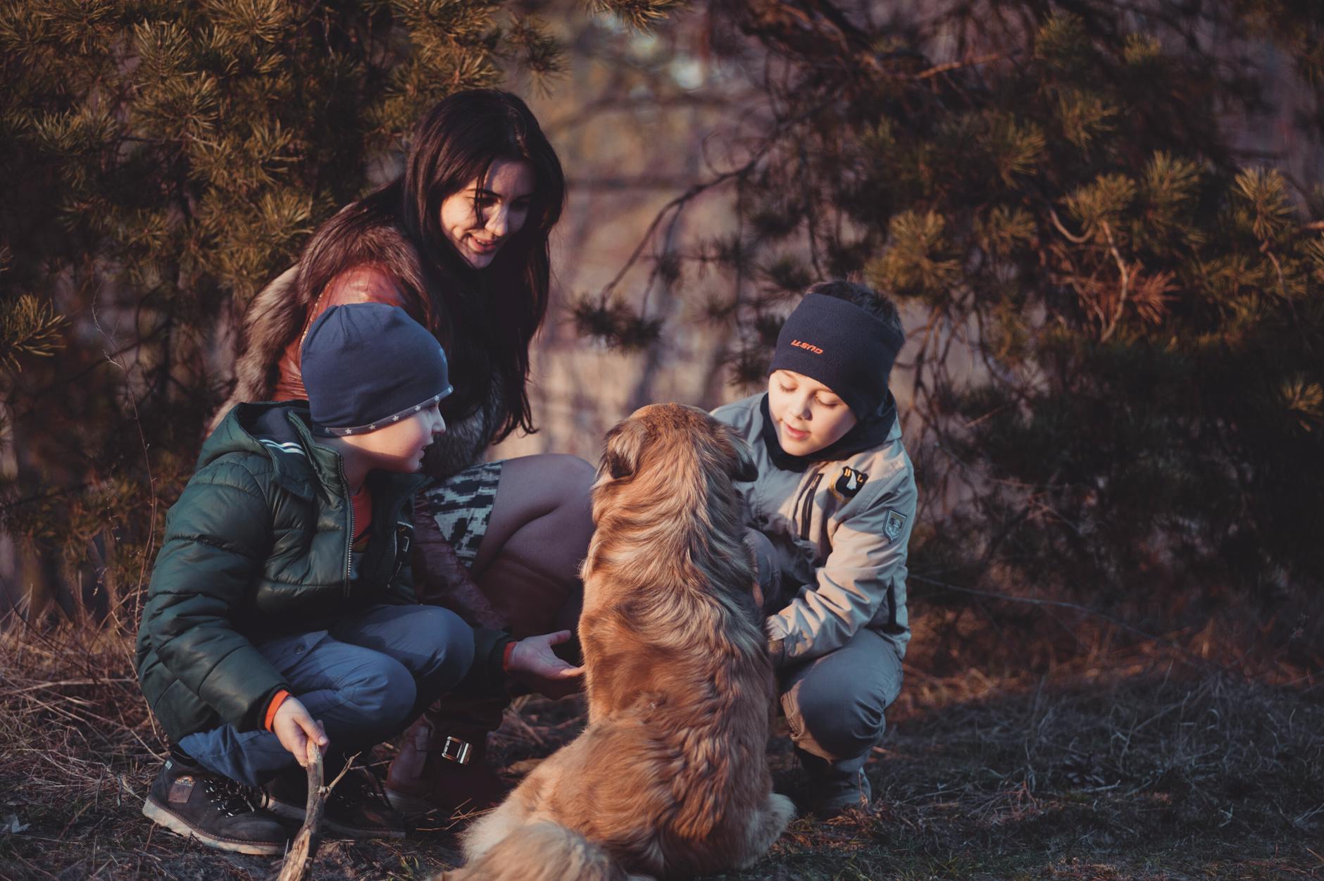 Family crouching beside a dog outdoors