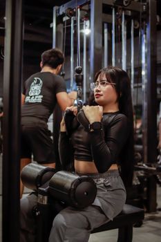 Young woman using a cable machine for strength training in a gym setting, promoting fitness and a healthy lifestyle.