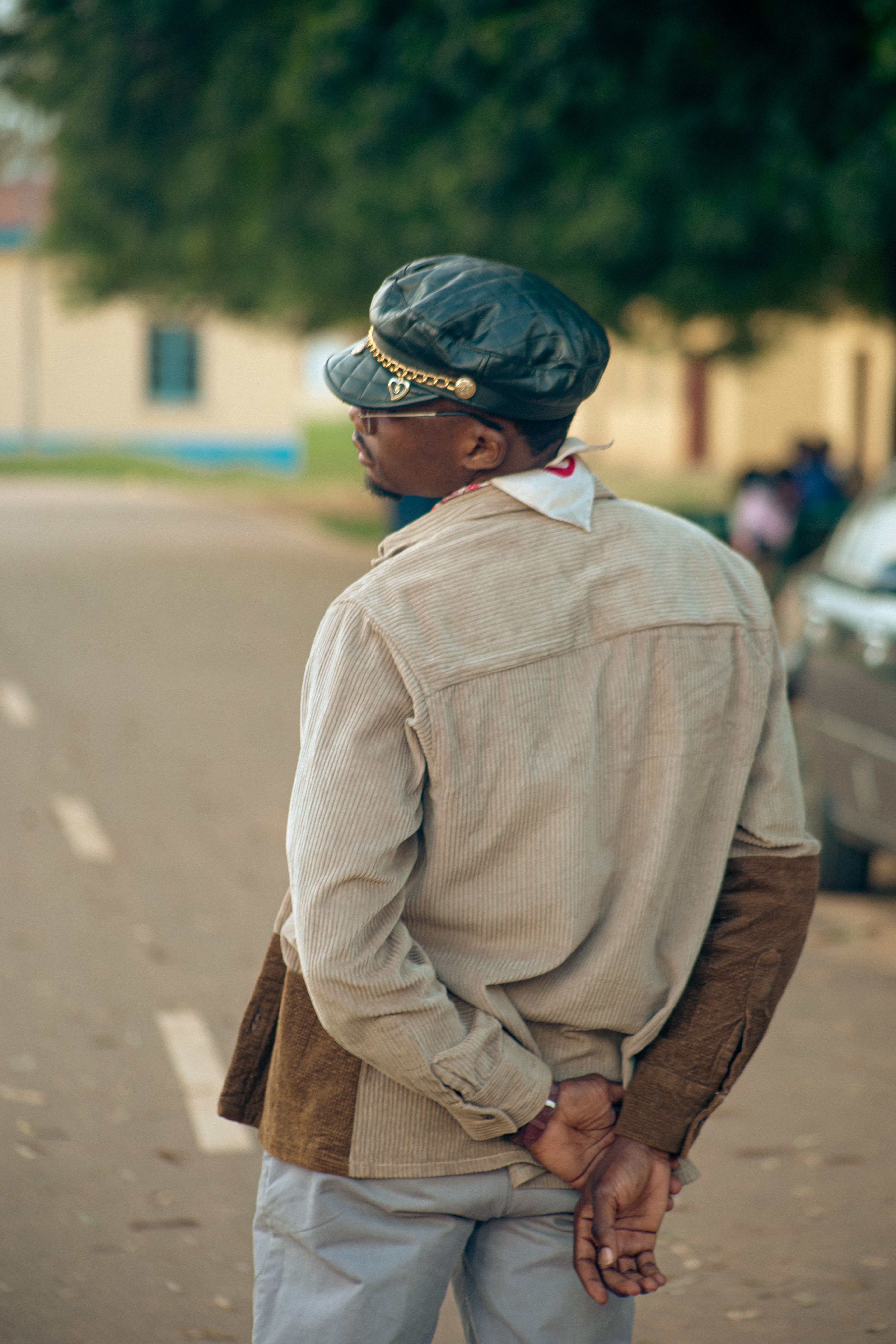 Rear view of a man in fashionable attire walking down a city street, exuding casual elegance.