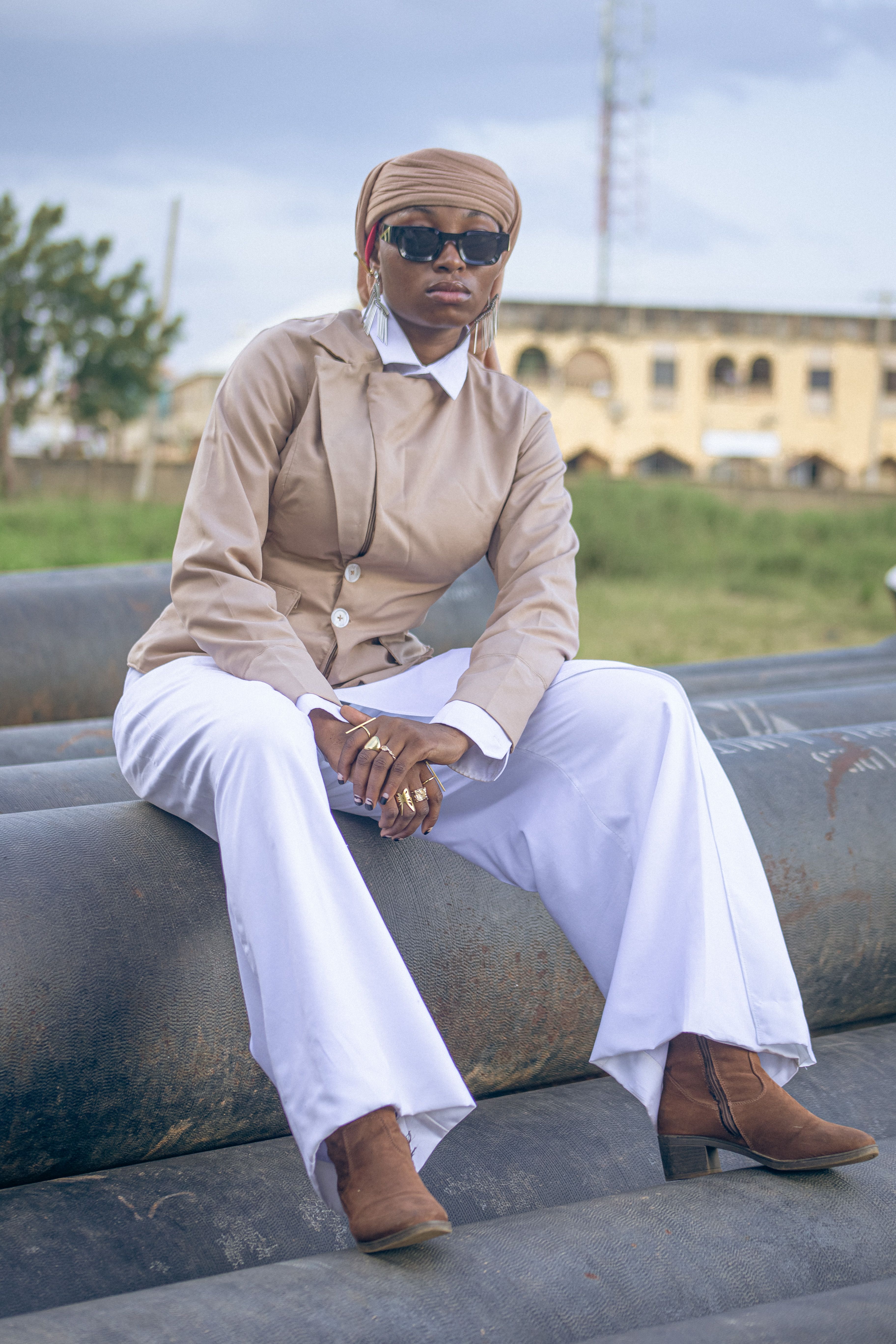 A fashionable woman in African attire poses confidently outdoors, showcasing contemporary style.