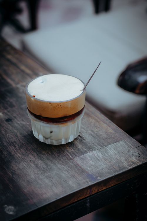 Free Chilled iced coffee with thick foam in a glass on a rustic table, evoking a cozy cafe vibe. Stock Photo