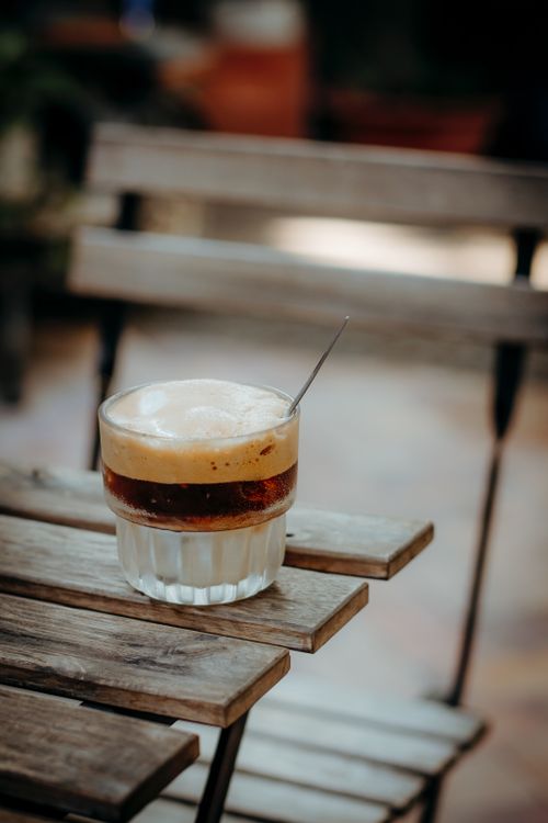 Free Refreshing iced coffee with frothy top on a rustic wooden table outdoors. Stock Photo
