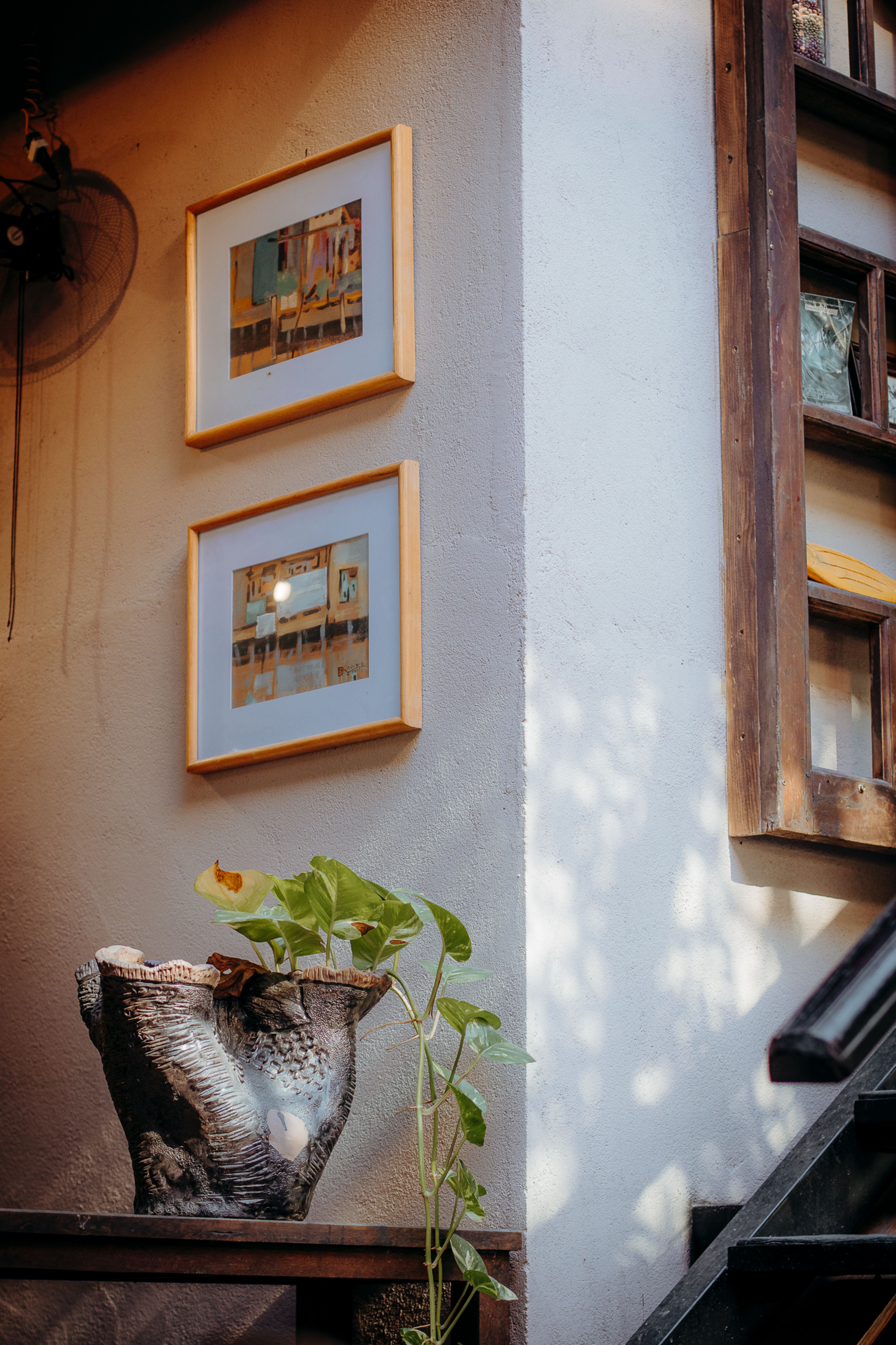 Warm indoor scene with framed art, lush plant, and rustic decor, creating an inviting atmosphere.